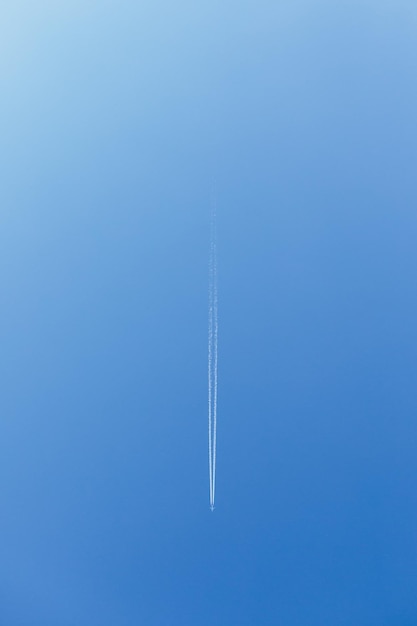 Rastro blanco de humo del avión volador Imagen vertical Avión volando en el cielo azul y línea de pista blanca viva Humo Avión