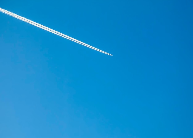 El rastro de condensación del avión y el avión en el cielo azul