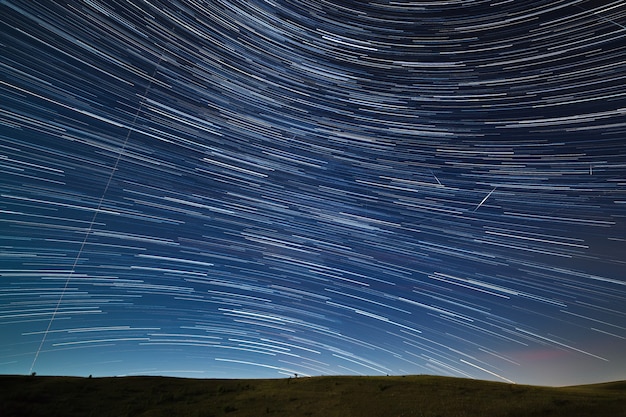 Rastro de estrellas en el cielo nocturno con meteoritos brillantes y luces de aviones.