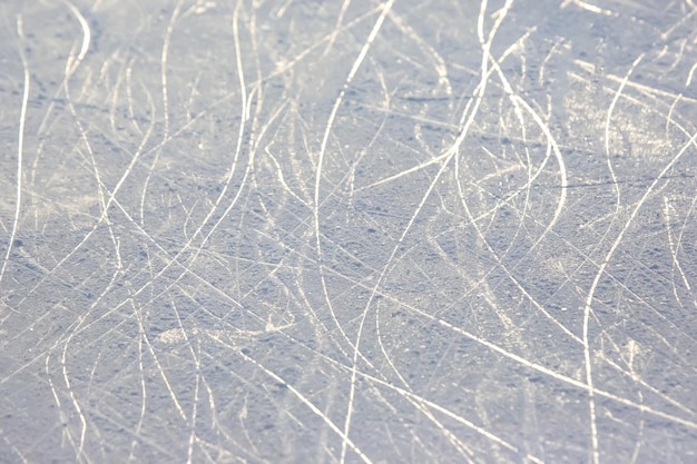 Rastros brillantes de patinaje sobre hielo en un fondo y textura de pista de hielo
