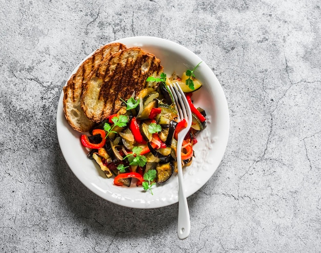 Ratatouille asado pan a la parrilla deliciosos aperitivos vegetarianos de la temporada de verano almuerzo merienda en una vista superior de fondo gris