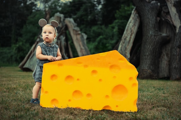 Ratinho bonitinho brincando com um grande pedaço de queijo na grama