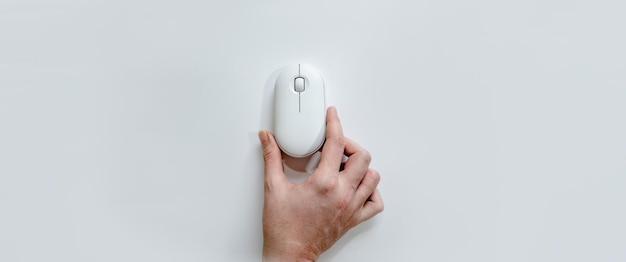 Ratón blanco de la computadora en la mano sobre un fondo blanco en formato de banner equipos informáticos y