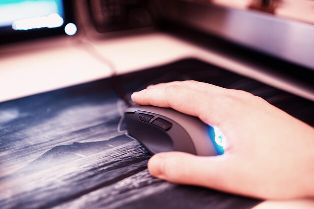 Ratón de la computadora con la mano humana en el mousepad bokeh como telón de fondo hd