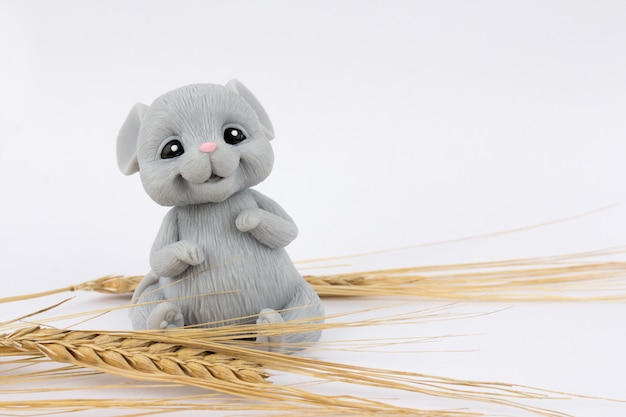 Ratón con espigas de trigo sentado sobre un blanco