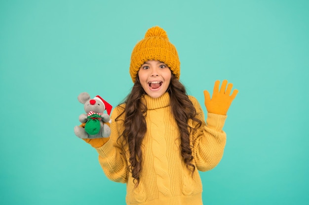 Ratón símbolo del año. linda niña sostiene un juguete de ratón. ropa de abrigo tejida para niños jugar con rata de juguete. tienda de juguetes para niños. comprar regalos de navidad. estar de humor navideño. feliz año nuevo 2020.