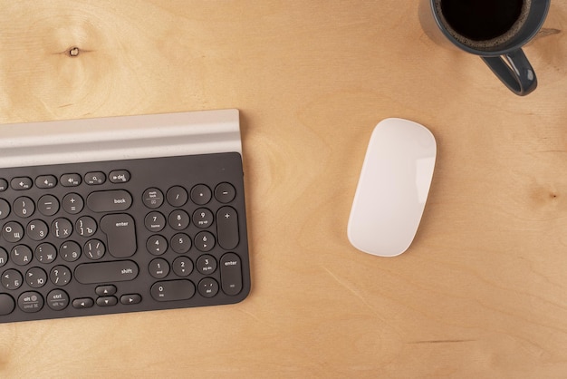 Foto ratón de teclado y taza de café sobre un fondo de madera clara concepto de lugar de trabajo lay flat