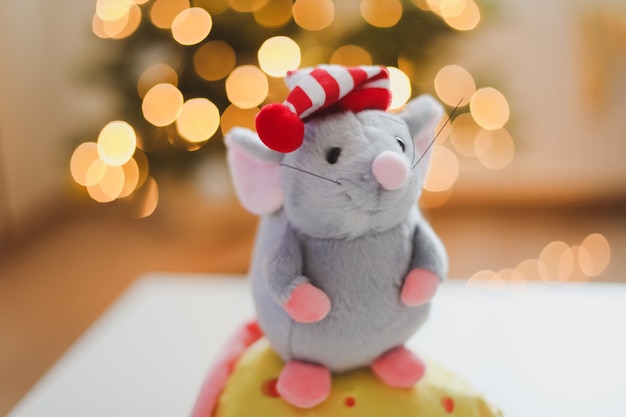 Ratoncito de juguete y adornos de año nuevo con luces bokeh de un árbol de Navidad