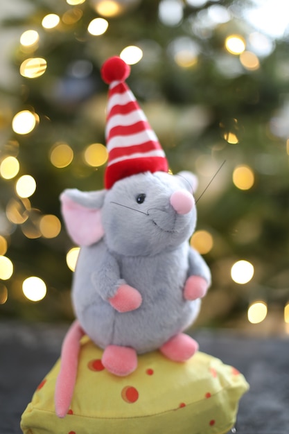 Ratoncito de juguete y adornos de año nuevo con luces bokeh de un árbol de Navidad