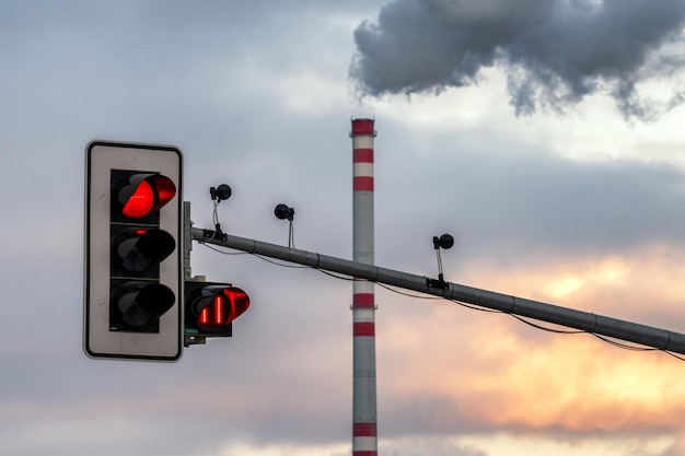 Rauch und Dampf aus dem Schornstein in der Fabrik und rotes Licht an Ampeln als Symbol für Luftverschmutzung