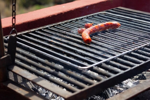 Rauchende heiße Würste, die auf dem Grill mit Holzkohle darunter kochen