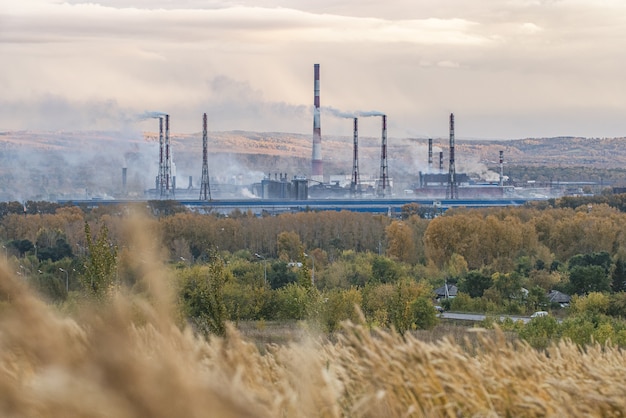 Rauchende Schornsteine einer Fabrik im Vordergrund der Holzkohle mit ausgereiften ikonischen Herbstpfannen