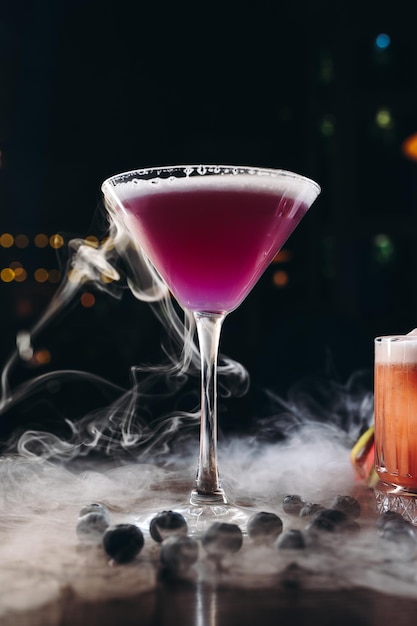 Rauchendes Martiniglas mit purpurrotem Getränk Cocktail mit Blaubeeren