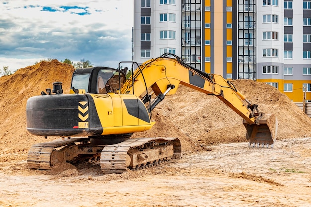 Raupenbagger-Maschine, die Sand oder Erde auf dem Baugrundstück entlädt. Nahaufnahme eines leistungsstarken Baggers. Vermietung von Baumaschinen. Erdbauunternehmer