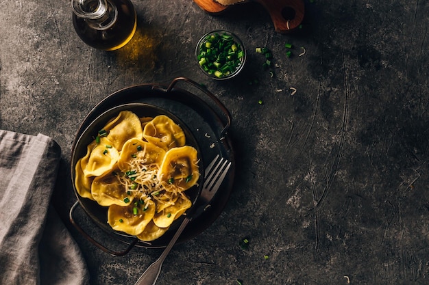 Ravioles italianos tradicionales rellenos de queso en un plato negro fondo oscuro Vista superior con espacio de copia