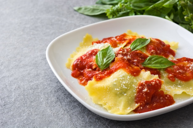 Ravioli com molho de tomate e manjericão em pedra cinza