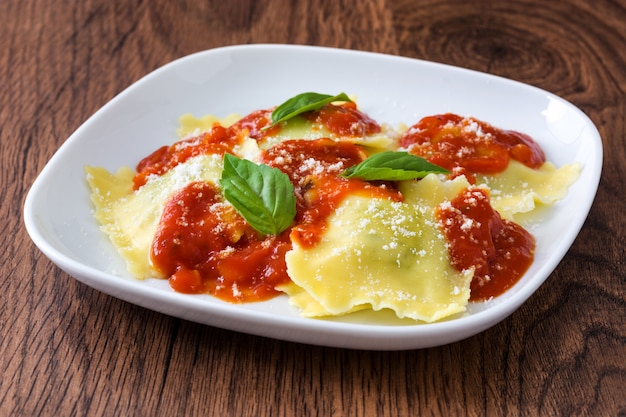 Ravioli com molho de tomate e manjericão na madeira