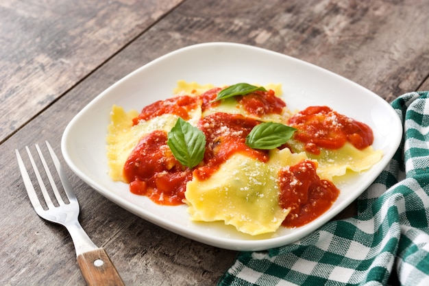 Ravioli com molho de tomate e manjericão na parede de madeira