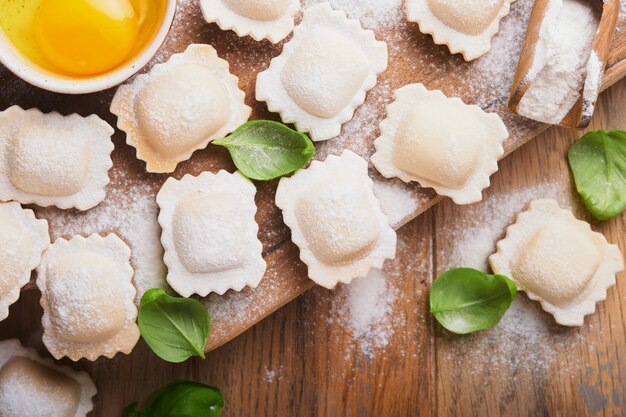 Ravioli Comida italiana Saboroso ravioli de massa caseira com farinha de tomate ovos e manjericão verde em fundo de madeira Processo de fazer ravioli italiano Fundo de ingredientes para cozinhar alimentos Vista superior