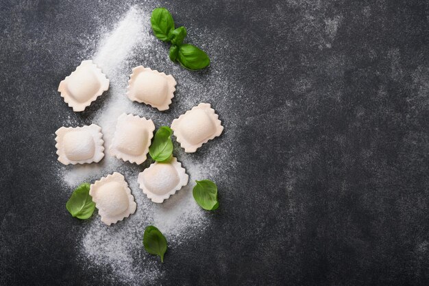 Ravioli Comida italiana Sabrosa casera con harina tomates huevos y albahaca verde sobre fondo oscuro Fondo de ingredientes de cocina Vista superior