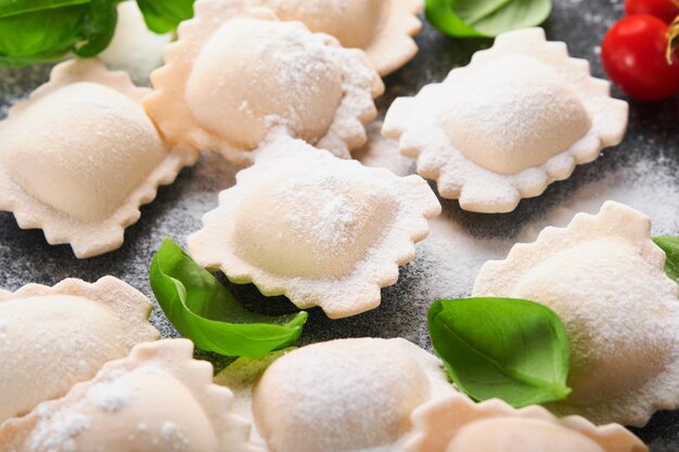 Ravioli Comida italiana Sabrosa casera con harina tomates huevos y albahaca verde sobre fondo oscuro Fondo de ingredientes de cocina Vista superior