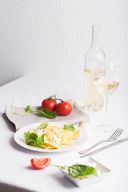 Ravioli cozido com manjericão, queijo e tomate na mesa branca