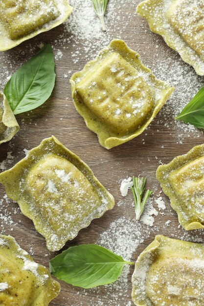 Ravioli cru com farinha e manjericão em fundo de madeira