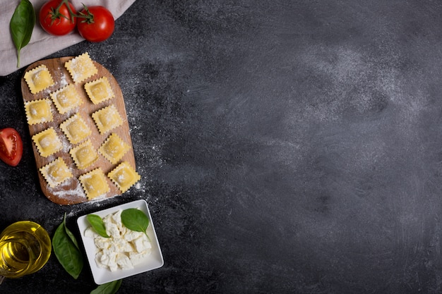 Ravioli cru com manjericão, queijo e tomate em fundo preto