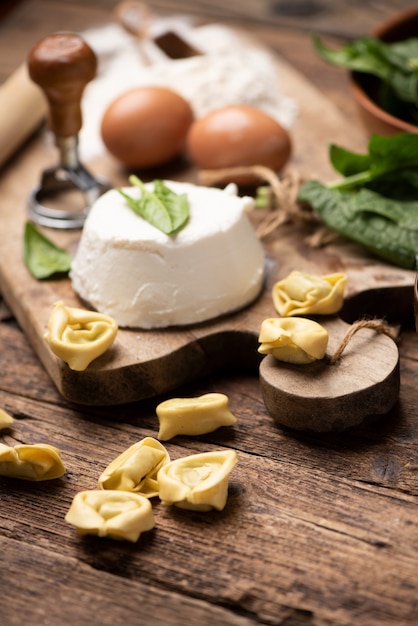 Ravióli de tortellini de carne em mesa rústica de madeira com espinafre e ricota