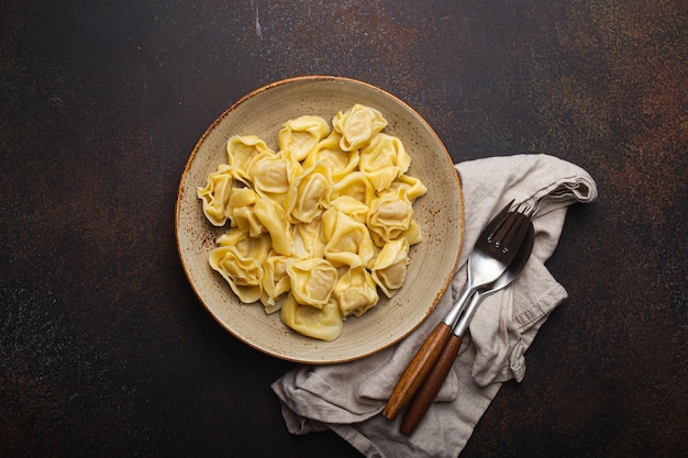 Foto ravioli de tortellini italiano recheado na placa vista superior na placa de pedra marrom