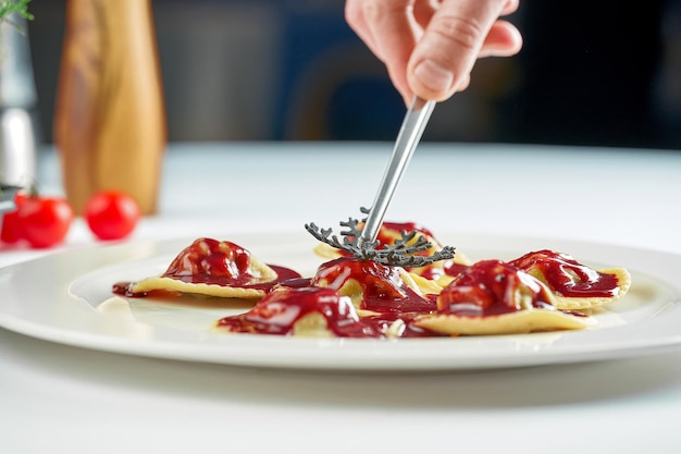 Ravioli in einer weißen Tellerzusammensetzung mit Zutaten, die das Gericht vom Küchenchef dekorieren