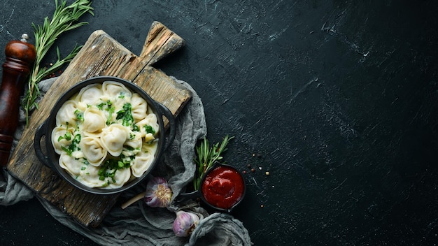 Ravioli mit Sahnesauce in einem schwarzen Teller. Italienische traditionelle Küche. Fleischbällchen. Ansicht von oben. Freier Kopienraum.