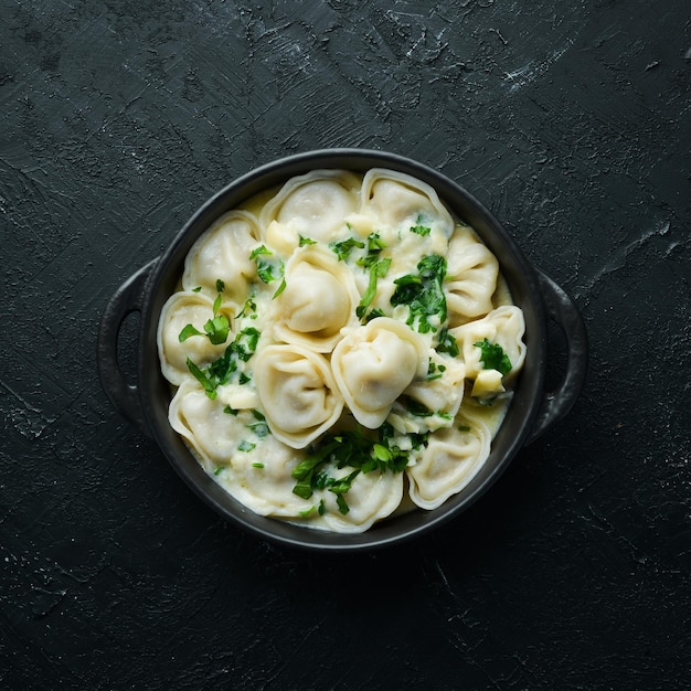 Ravioli mit Sahnesauce in einer schwarzen Platte Traditionelle italienische Küche Fleischknödel Draufsicht Freier Kopierbereich