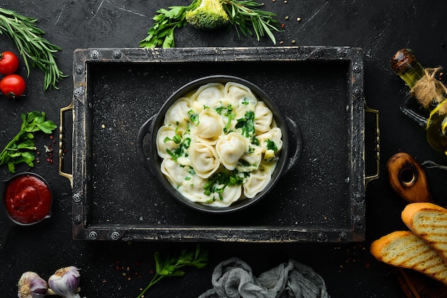 Ravioli mit Sahnesauce in einer schwarzen Platte Traditionelle italienische Küche Fleischknödel Draufsicht Freier Kopierbereich