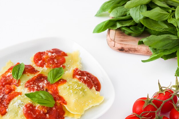 Foto ravioli mit tomatensauce und basilikum auf weiß