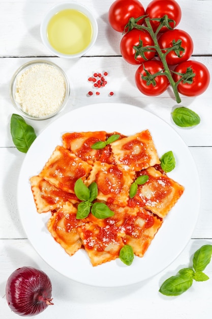 Ravioli Nudelgericht aus Italien zum Mittagsgericht mit Tomatensauce Draufsicht auf einem Teller und Holzbrett Hochformat