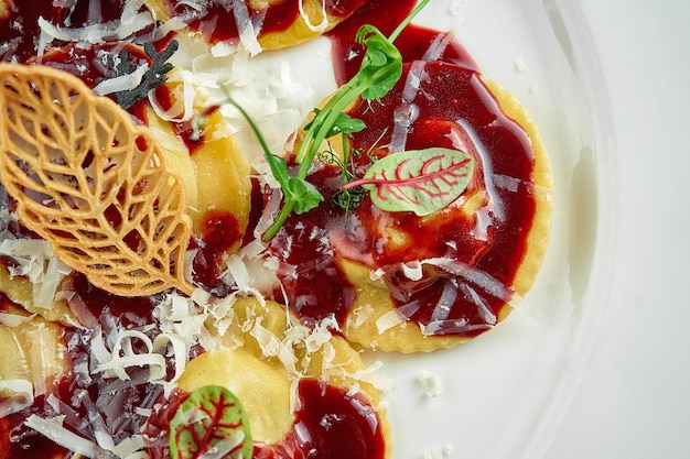 Ravioli con salsa y mejillas de ternera parmesano en un plato blanco sobre un mantel blanco Cerrar el enfoque selectivo