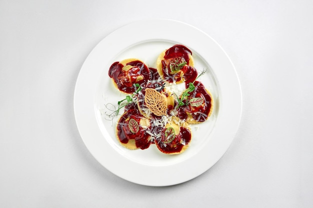 Ravioli con salsa y mejillas de ternera parmesano en un plato blanco sobre un mantel blanco