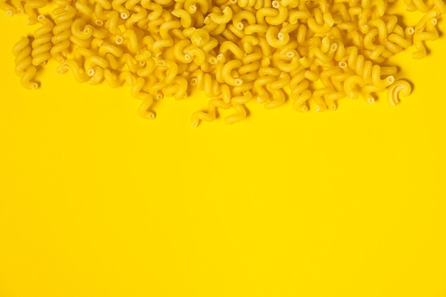 Raw Cavatappi Cellentani fideos pasta comida italiana macro sobre fondo amarillo