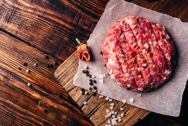 Raw Round Patty mit Gewürzen auf Wachspapier für Burger. Von oben betrachten.