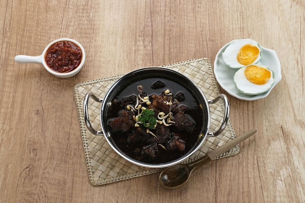 Rawon, sopa tradicional indonésia de carne preta. Servido em uma tigela com brotos de feijão mungo, pasta de pimenta