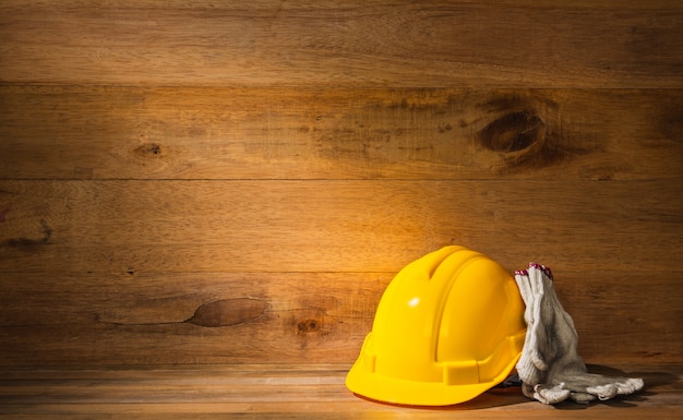 Rayo de luz que cae en el casco de seguridad del ingeniero o capataz y guantes en la mesa de madera