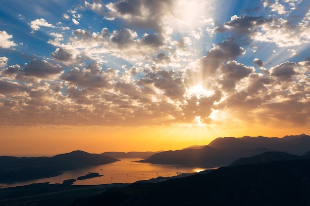 Rayos del atardecer naranja en el cielo azul sobre la vista de la bahía de kotor desde el monte lovcen