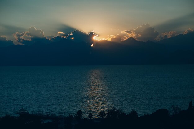 Foto rayos dramáticos del atardecer a través del cielo oscuro nublado sobre el océano