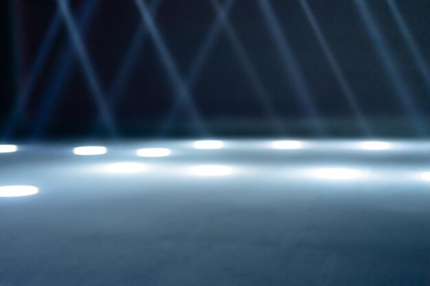 Rayos de luz borrosos en el piso de la discoteca luces de reflector de neón azul blanco líneas láser y efecto de iluminación escenario vacío nocturno en estudio con reflejos de neón escena de fondo espacial abstracto oscuro