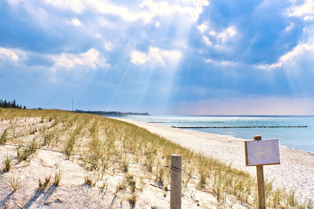 Los rayos del sol brillan a través de espesas nubes en la playa del cruce de la playa Baltic SeaSign