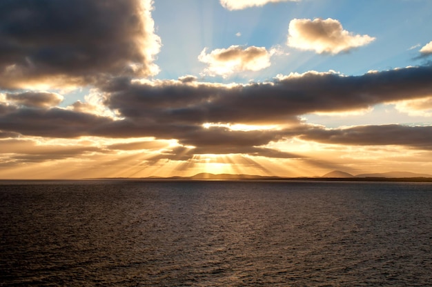 Rayos de sol saliendo de las nubes al atardecer sobre el mar