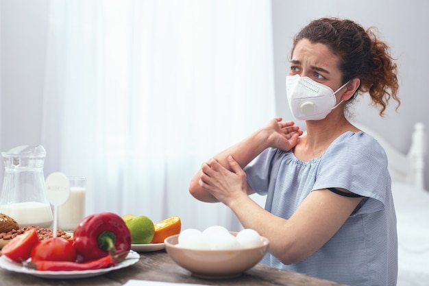 Razón en la comida. Señora adolescente que parece preocupada experimentando picazón alérgica en el codo causada por algunas alergias alimentarias