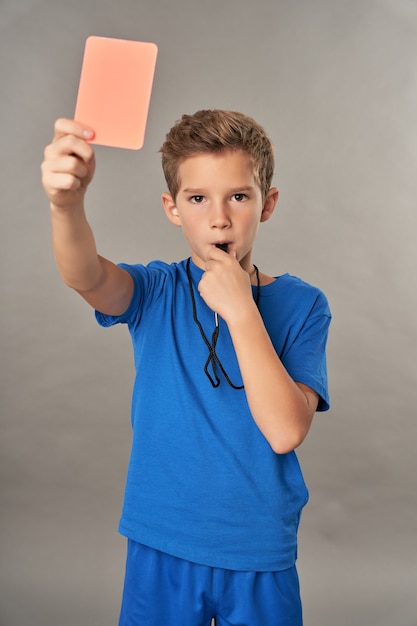 Árbitro de chico lindo con tarjeta roja y silbido en el silbato