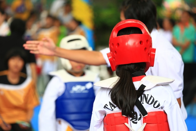 Árbitro dá sinal para jovens atletas de Taekwondo